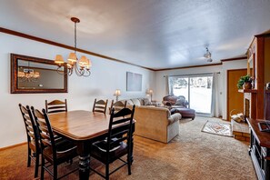 A dining area with a wooden table and chairs, a chandelier, and a large mirror. - Park Station 218 2 Bedroom Condo by RedAwning (Park City)