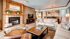 A living room with a fireplace, sofa, coffee table, and television. - Park Station 218 2 Bedroom Condo by RedAwning (Park City)