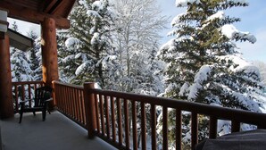A wooden deck with a railing, a chair, and snow-covered trees in the background. - Snow Flower 071 3 Bedroom Condo by RedAwning (Park City)