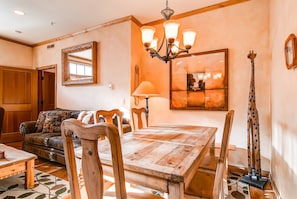 A dining area with a wooden table and chairs, a chandelier, and a giraffe sculpture.