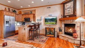 Cocina moderna con armarios de madera, un refrigerador de acero inoxidable y una chimenea de piedra.