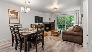 A dining area with a wooden table set for four, a sofa, and a fireplace. - Snow Flower 134 2 Bedroom Condo by RedAwning (Park City)