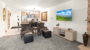 A modern living room with a dining area and kitchen in the background.