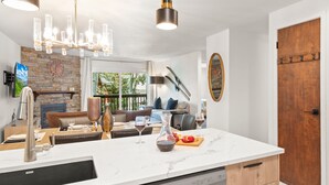 A modern kitchen with a white marble countertop, a built-in dishwasher, and a dining area with a wooden table and chairs.