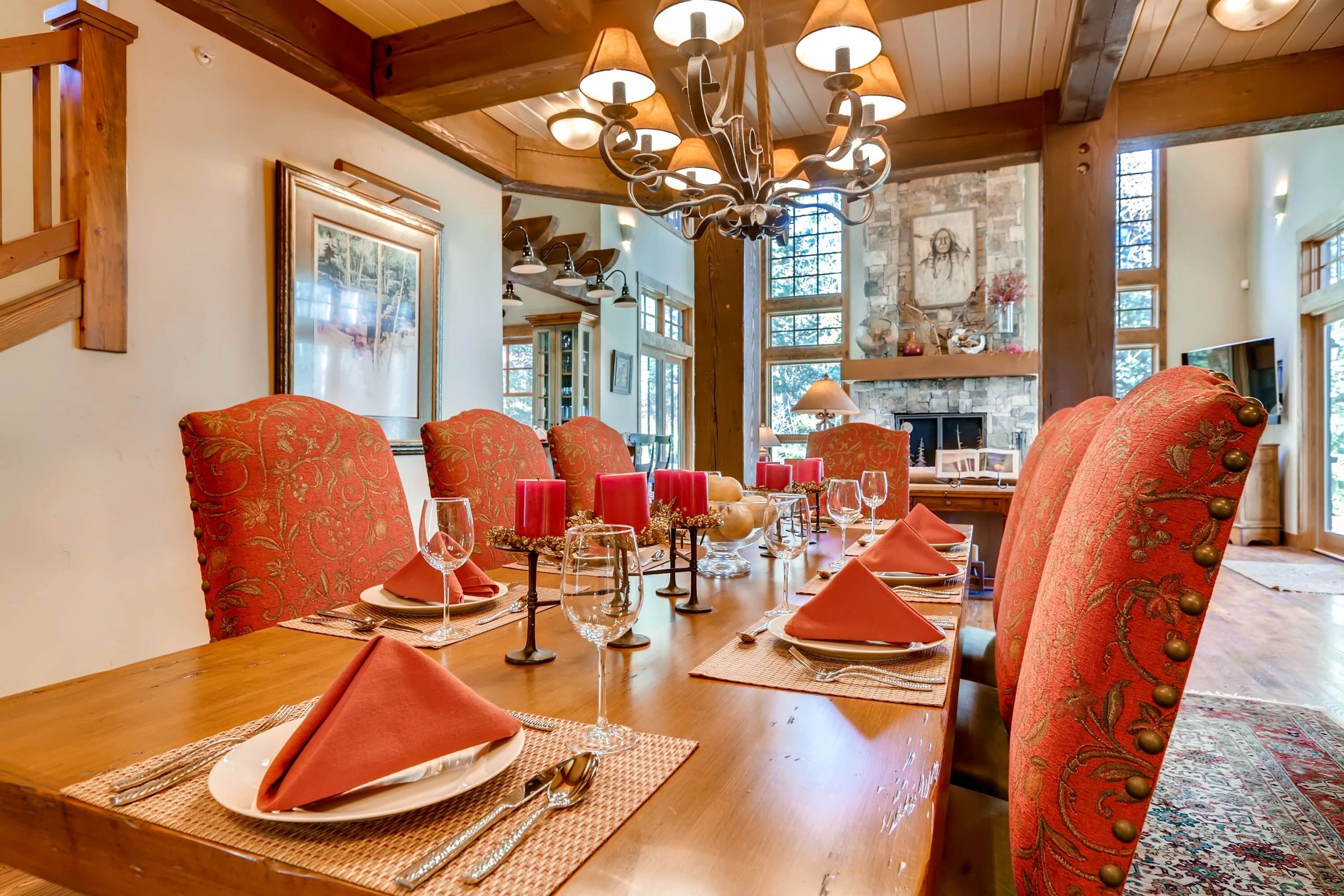 A dining area with a wooden table set for six, red upholstered chairs, and a chandelier.