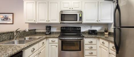 A modern kitchen with white cabinets, stainless steel appliances, and granite countertops.
