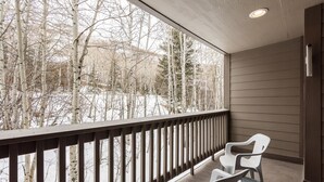 Un balcon donnant sur un paysage enneigé, avec une balustrade en bois et deux chaises blanches.