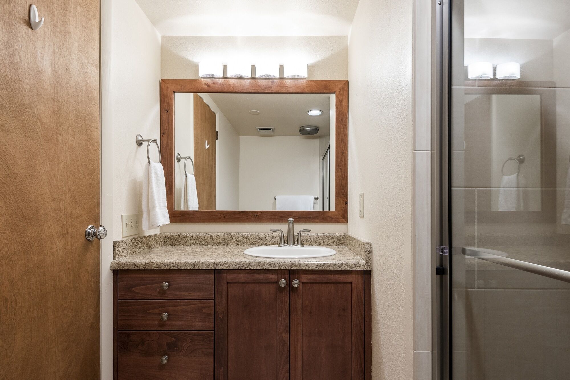 A bathroom with a wooden vanity, a sink, and a mirror.