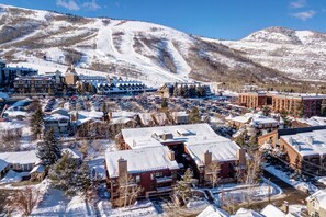 A snow-covered town with a ski resort in the background, featuring a mix of residential and commercial buildings.
