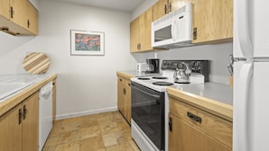 A modern kitchen with wooden cabinets, a white microwave, a stove, and a dishwasher. - Fashion Coalition 402 2 Bedroom Condo by RedAwning (Park City)