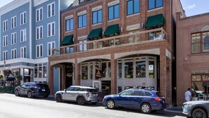 A multi-story building with a ground-floor restaurant and a second-floor bar. There are cars parked in front, and a person is visible near the entrance. - Fashion Coalition 402 2 Bedroom Condo by RedAwning (Park City)