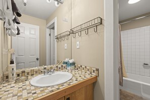 A bathroom with a tiled vanity, a sink, a mirror, and a shower area. - Fashion Coalition 402 2 Bedroom Condo by RedAwning (Park City)