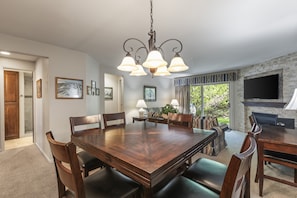 Uma sala de jantar com uma grande mesa de madeira, cadeiras, um candelabro e uma lareira.