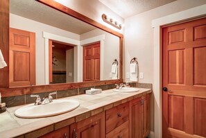 A bathroom with two sinks, wooden cabinets, a large mirror, and a door. - Town Pointe B303 3 Bedroom Condo by RedAwning (Park City)