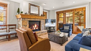 A cozy living room with a stone fireplace, comfortable seating, and large windows. - Town Pointe C101 3 Bedroom Condo by RedAwning (Park City)