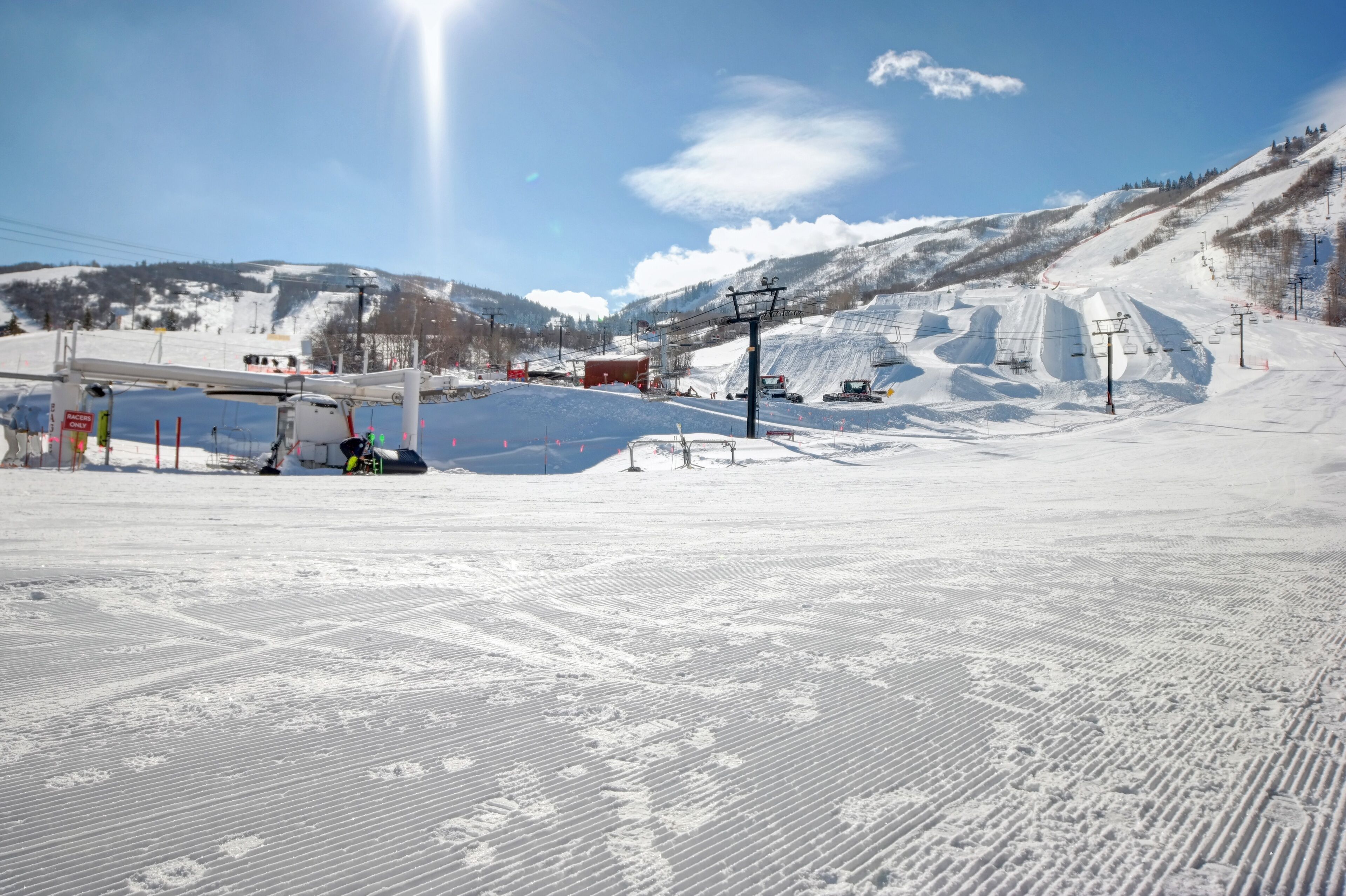 A ski resort with a chairlift, ski slopes, and a mountain backdrop.
