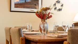 A dining table set with chairs, a vase of dried flowers, and a framed landscape painting on the wall. - Snow Flower 159 2 Bedroom Condo by RedAwning (Park City)
