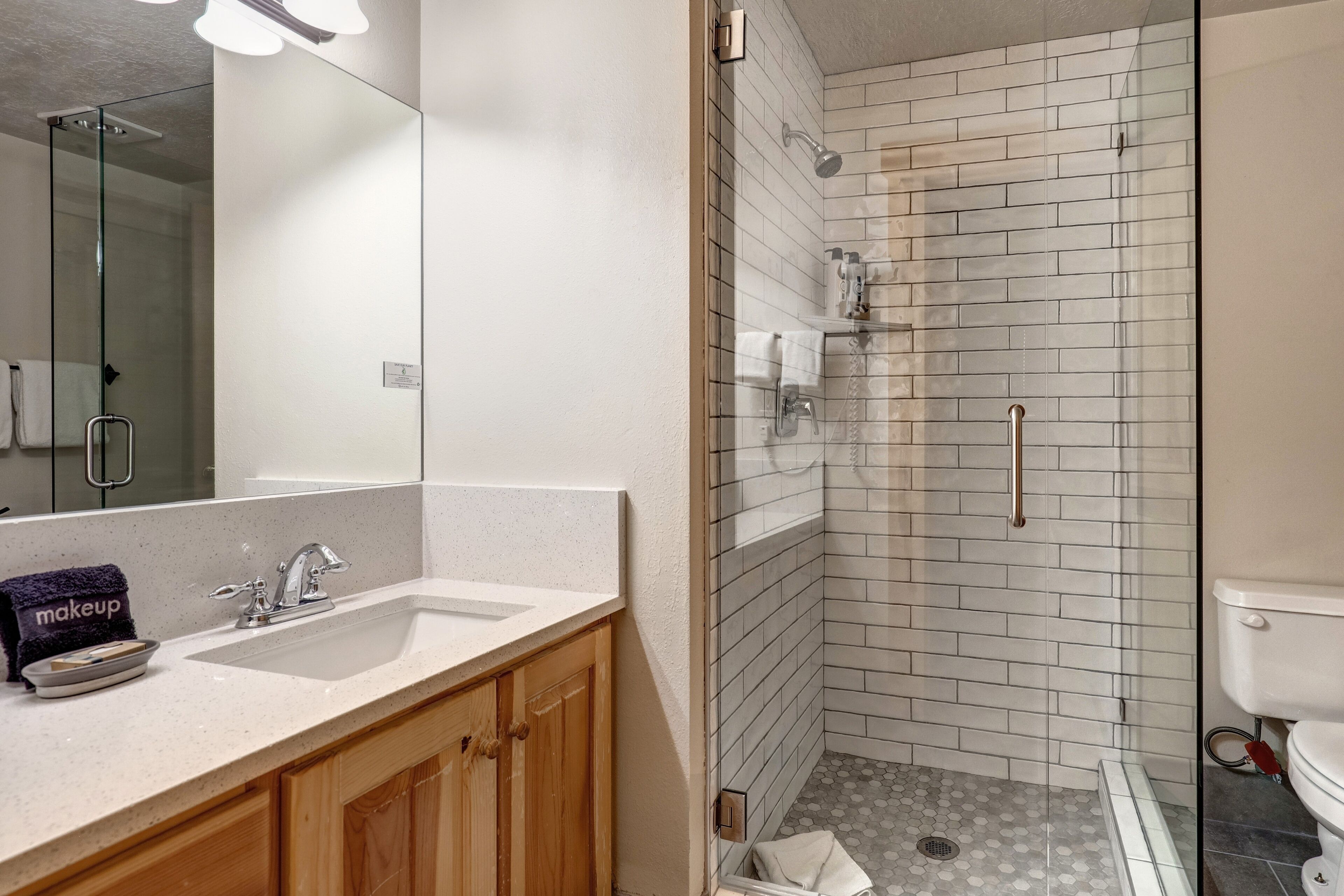 A bathroom with a sink, mirror, and shower area.