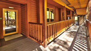 En stuga byggd av trä med en inglasad veranda och en dörr som leder ut till en terrass.