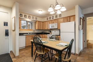 Kitchen with a central island, microwave, stove, refrigerator, and dining table with chairs.