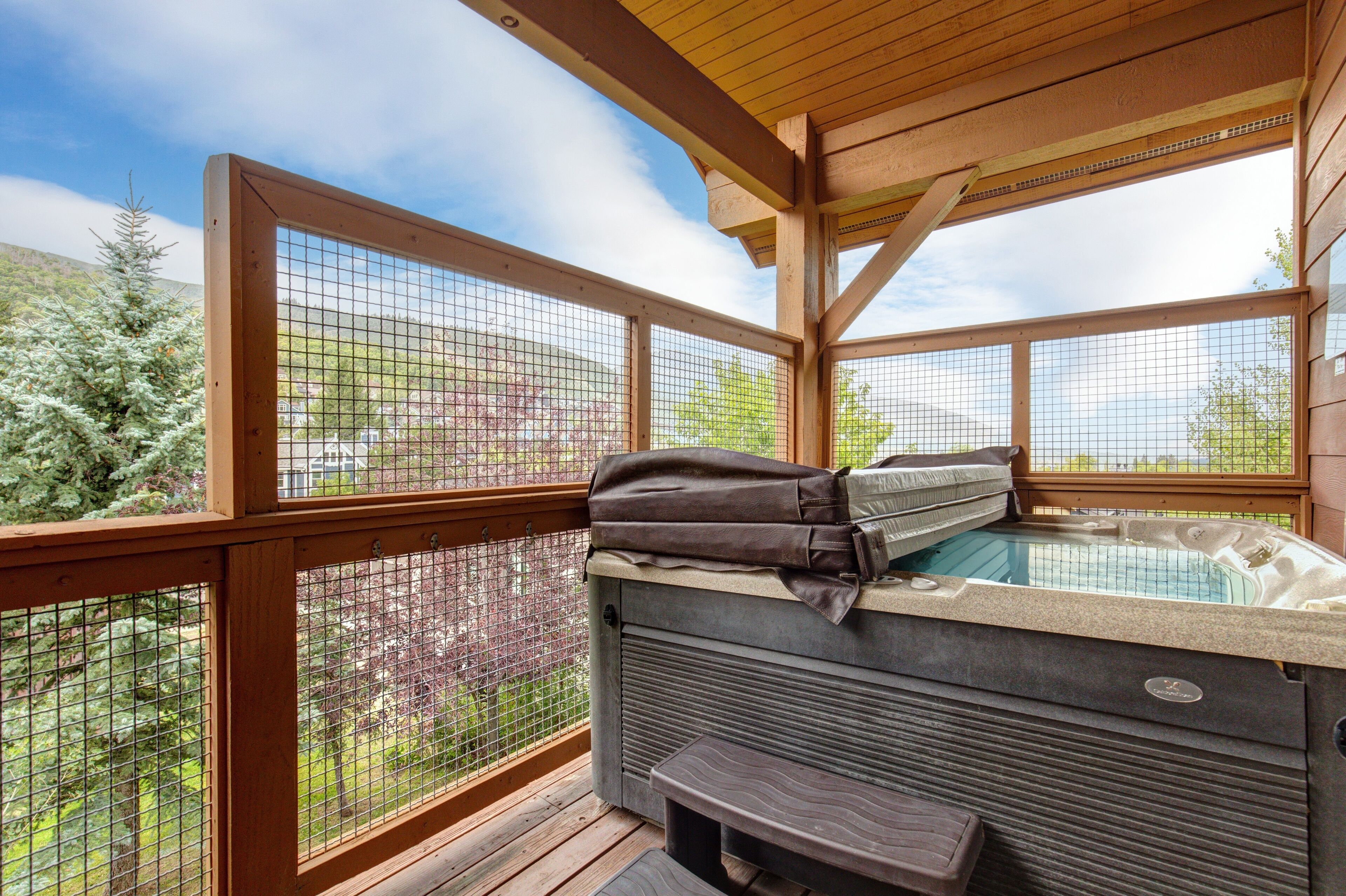 A hot tub with a wooden deck and a view of a garden.