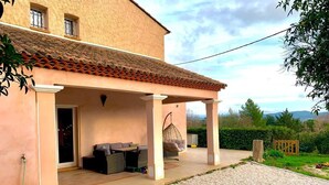 A house with a covered patio, a hanging chair, and a gravel driveway. - Maison de Campagne Avec Jardin (Cuers)