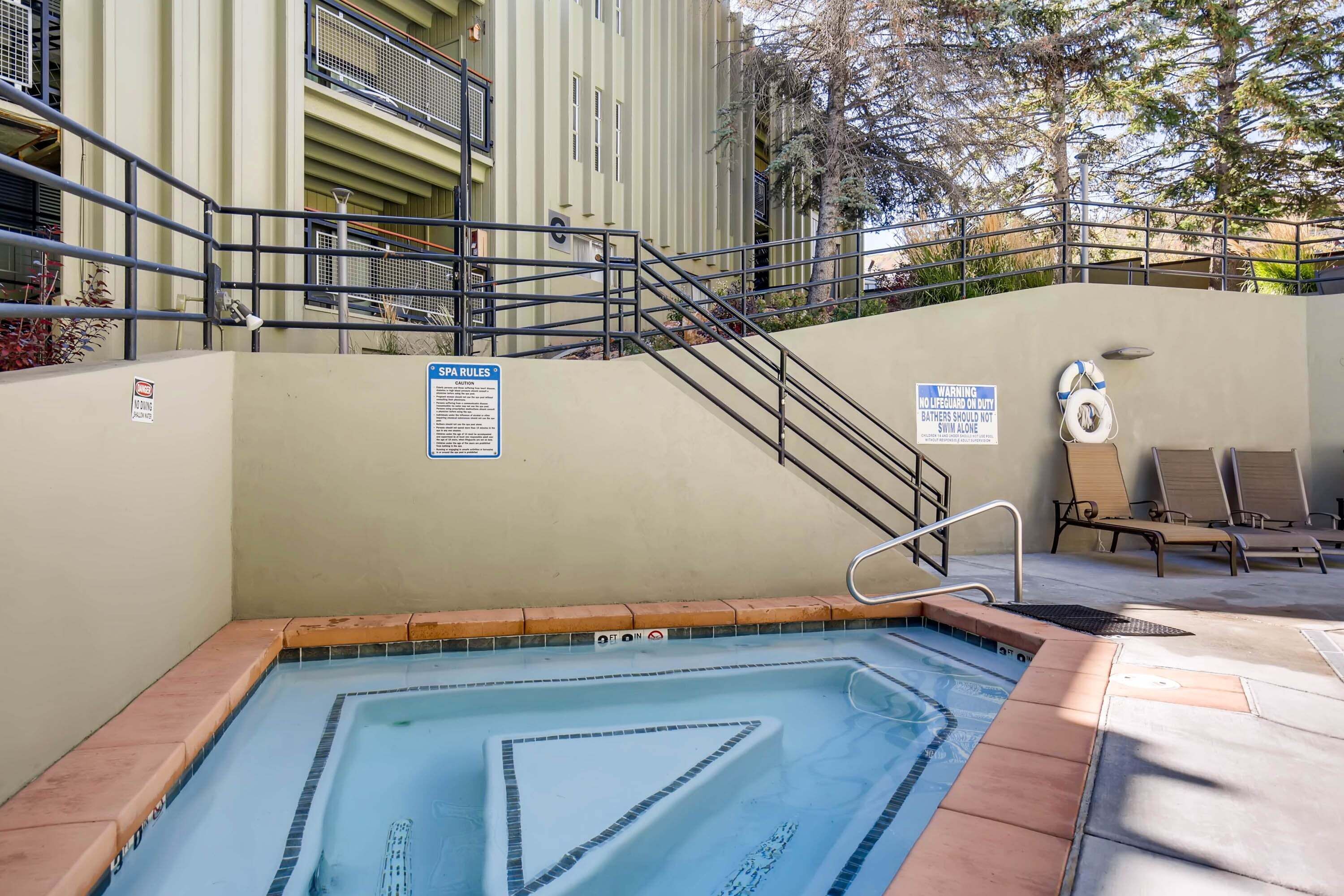 Uma piscina com um posto de salva-vidas, uma placa com regras da piscina e um círculo salva-vidas.