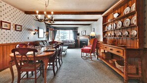 A traditional dining room with a wooden table, chairs, and a chandelier. There is a fireplace and a sofa in the background. - Snow Flower 062 3 Bedroom Condo by RedAwning (Park City)