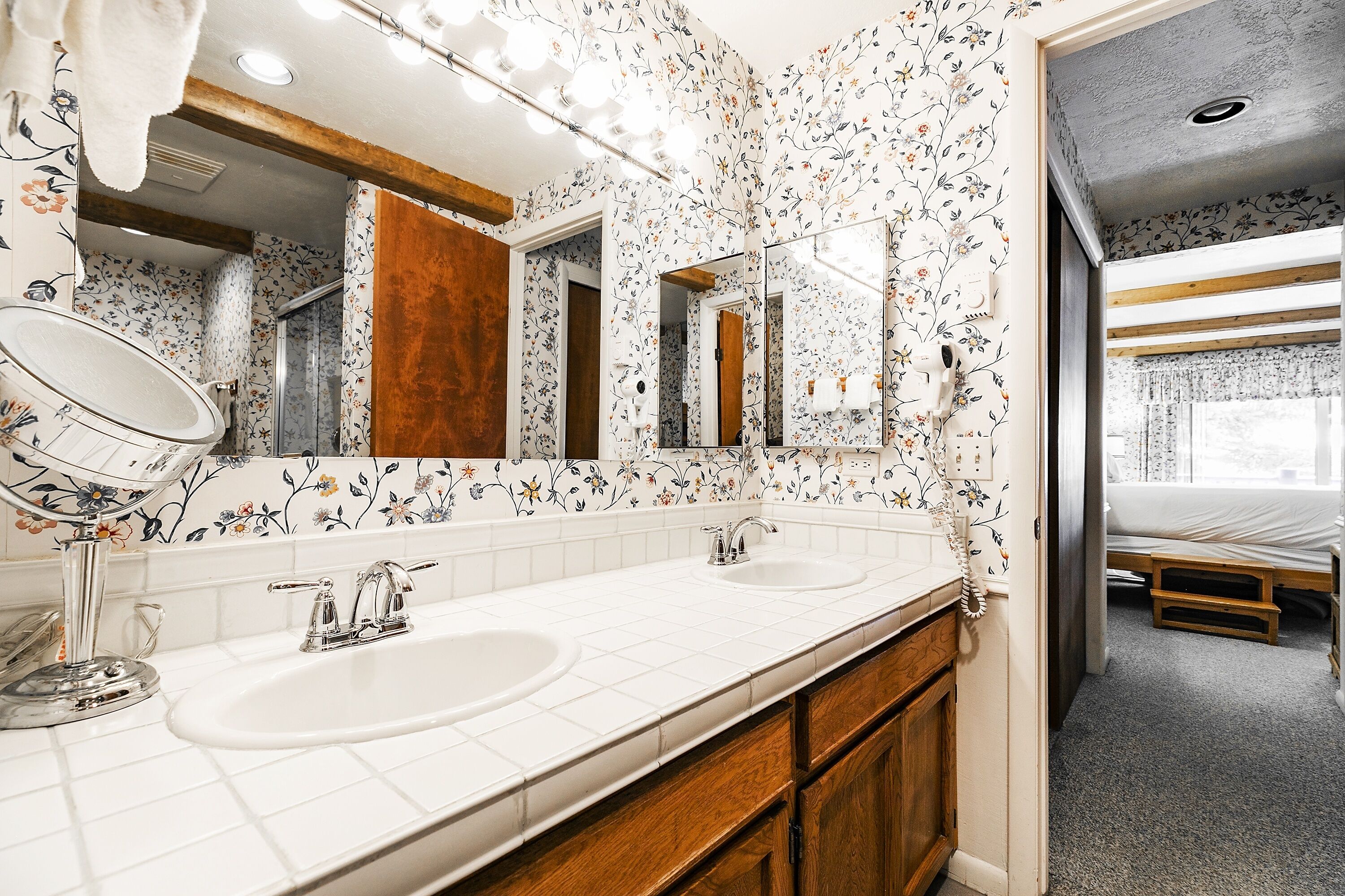 A bathroom with two sinks, a mirror, and a shower.