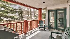 A covered porch with a red railing, two green chairs, and a table with chairs inside. - Snow Flower 062 3 Bedroom Condo by RedAwning (Park City)
