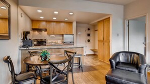 Una cocina moderna con armarios de madera, una isla central y un comedor con mesa y sillas redondas.