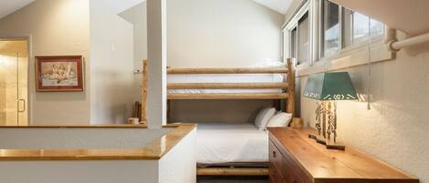 A compact bedroom with a bunk bed, a wooden dresser, and a framed picture on the wall.