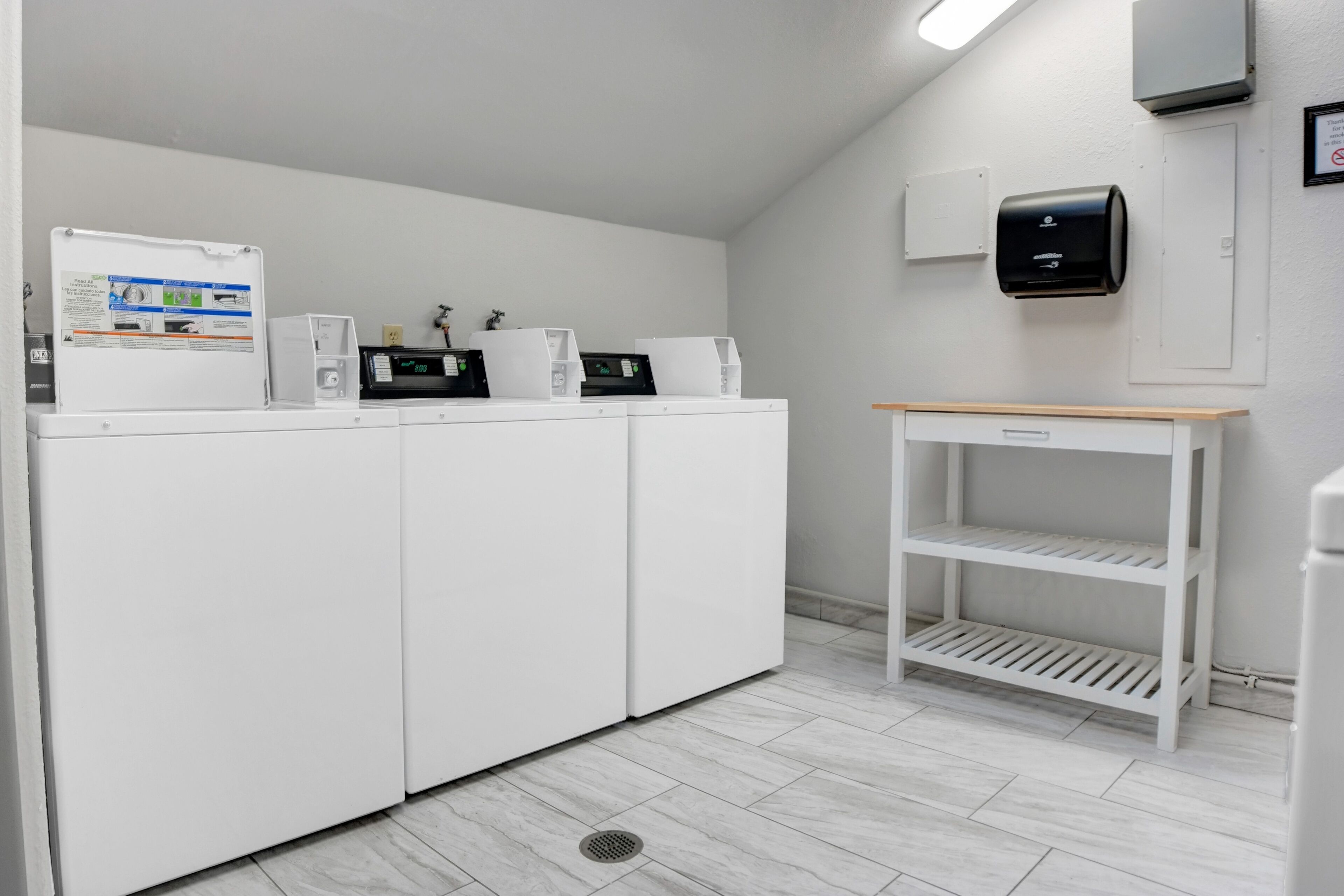 A laundry area with white appliances, a small table, and a wall-mounted air purifier.