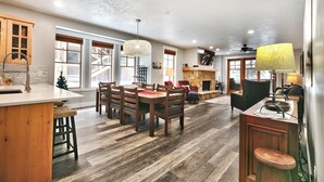 A spacious kitchen with a dining area, wooden flooring, and a large island.