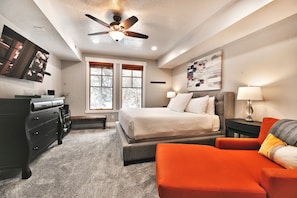 A bedroom with a bed, a desk, a chair, and a ceiling fan.