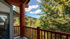 A wooden balcony with a red railing overlooking a forested mountain area. - Snow Flower 028 3 Bedroom Condo by RedAwning (Park City)