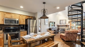 A modern kitchen with wooden cabinets, stainless steel appliances, and a dining area with a wooden table and benches.