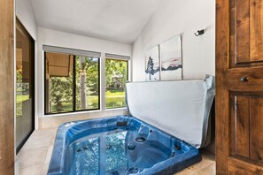 A spa room with a hot tub, large windows, and artwork on the wall.