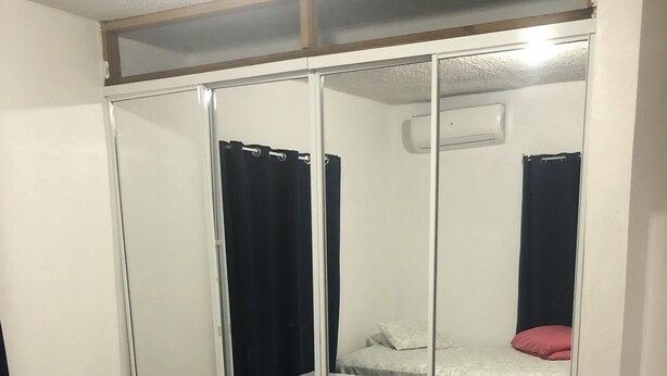 Un dormitorio con cama, mesita de noche pequeña, armario y espejo.