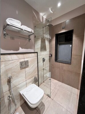 Un baño moderno con cabina de ducha de vidrio, inodoro y perchero para toallas.