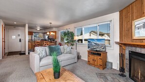 A spacious living room with a grey sofa, a wooden coffee table, and a fireplace.