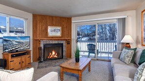 A cozy living room with a fireplace, a television, and a sofa.