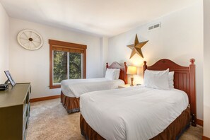 A room with two beds, a desk, a window, and a star decoration on the wall.