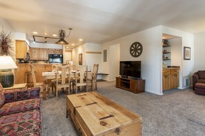 Un salon spacieux avec une table basse en bois, un téléviseur et un jeu de fléchettes.
