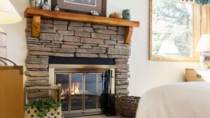 A stone fireplace with a glass door, a wooden mantel shelf, and a framed picture above it. - Snow Flower 067 2 Bedroom Condo by RedAwning (Park City)