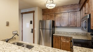 A kitchen with granite countertops, stainless steel appliances, wooden cabinets, and a built-in oven. - Snow Flower 109 2 Bedroom Condo by RedAwning (Park City)