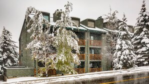 Ein mehrstöckiges Gebäude mit Balkonen, umgeben von schneebedeckten Bäumen.
