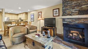 A living room with a fireplace, a television, and a dining area in the background.