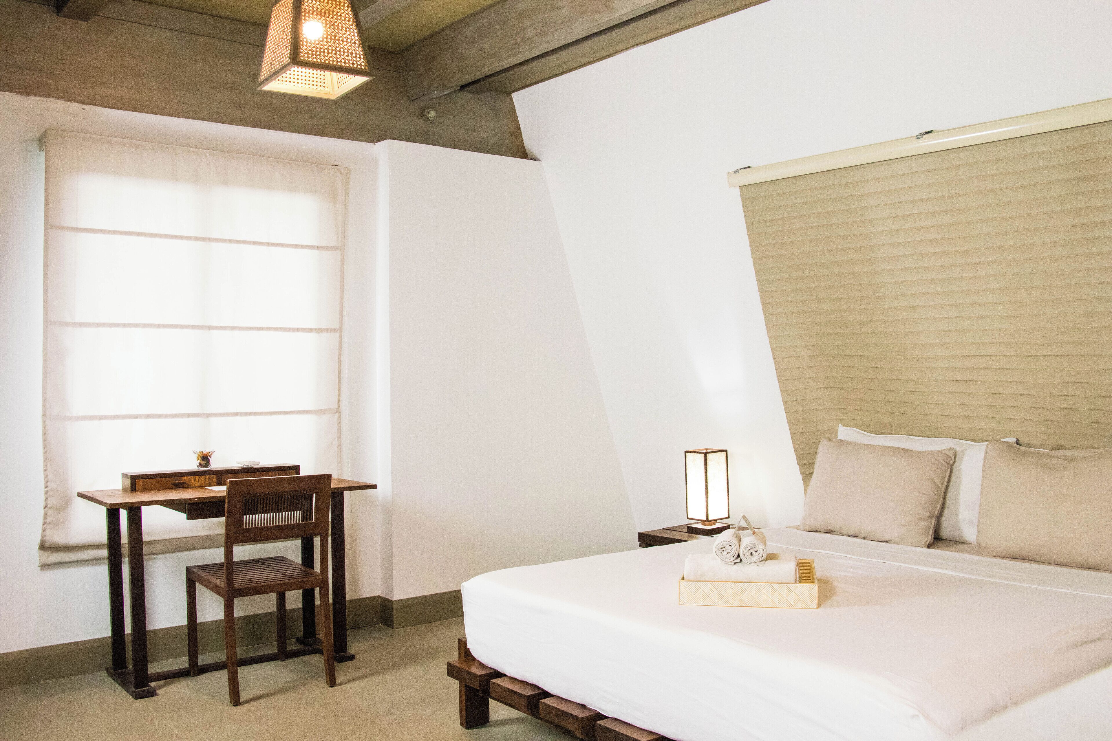 A bedroom with a bed, a desk, and a chair.