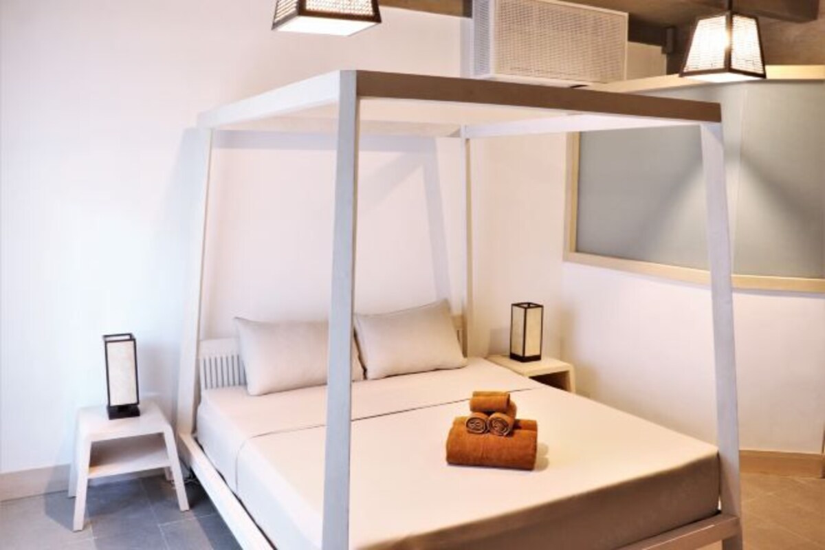 A modern bedroom with a four-poster bed, a small bedside table, and a nightstand with a lamp.